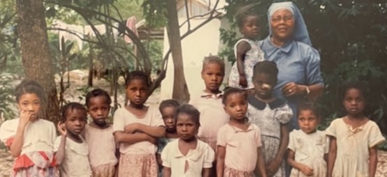 A woman standing with a group of children outdoors.